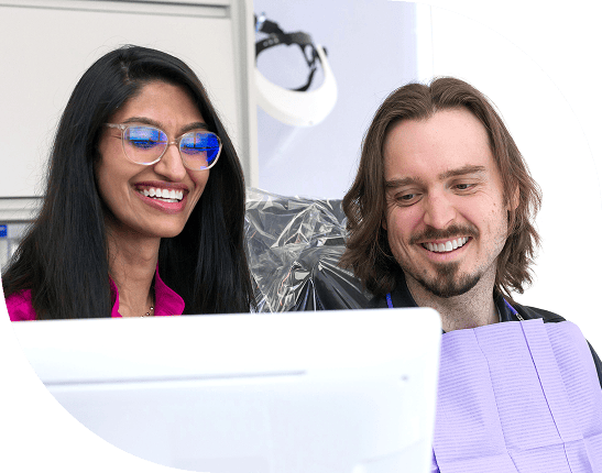 Dentist and patient smiling at a computer.
